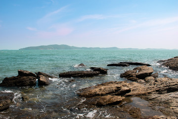 Fototapeta na wymiar Rocky sea with splashing wave and far away one of the most famous island in Thailand.