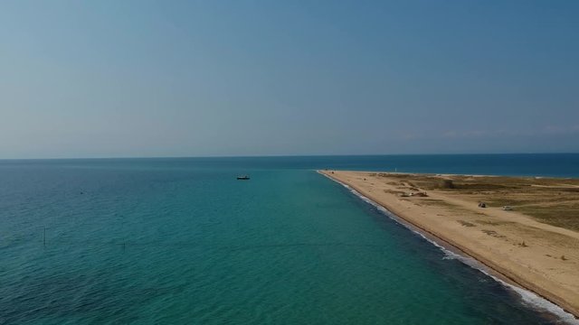 Ascending revealing aerial drone shot of a peninsula that extends into the ocean over a golden sandy shore and  the blue sea of Mediterranean sea close to Thessaloniki, Greece in Epanomi