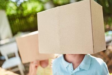 Children hide their faces under cardboard boxes
