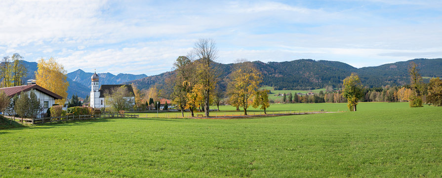 rural landscape with village church Fischbachau and autumnal trees, tourist resort bavaria