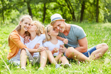 Naklejka na ściany i meble Happy family is sitting relaxed in the garden