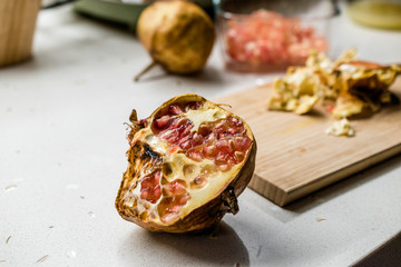 Half Cut Raw Organic Ripe Pomegranate with Seeds on Kitchen Surface.