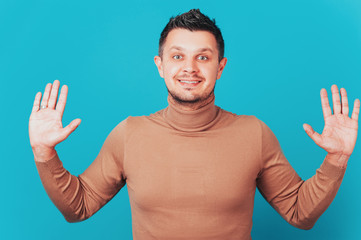 Naklejka premium Merry man spreads palms, has joyous expression, white teeth, makes decision, gets unexpected offer. young male stands with palms outstretched in camera, looks surprisingly at camera.