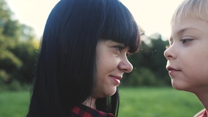 happy family mom and a son concept. son kisses mom tender childhood video. slow motion video. mom brunette girl gently hugs lifestyle takes care of the boy son blonde outdoors