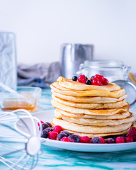 Pancakes with berries with pastry objects in the background.