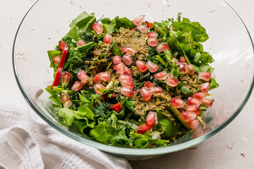 Homemade Salad with Pomegranate Seeds and Herbal Plant Root Sauce Mixed with Two Spoon in Glass Bowl.