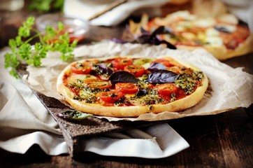 Pizza margarita with pesto on a dark wooden background