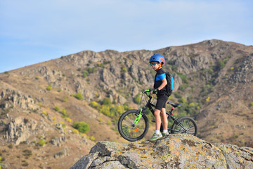 Fototapeta na wymiar Happy kid boy of 7 years having fun in autumn park with a bicycle on beautiful fall day. Active child wearing bike helmet