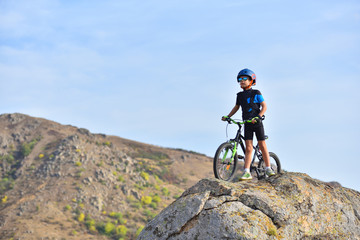 Fototapeta premium Happy kid boy of 7 years having fun in autumn park with a bicycle on beautiful fall day. Active child wearing bike helmet