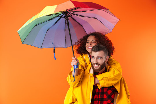 Loving couple posing in yellow raincoats isolated