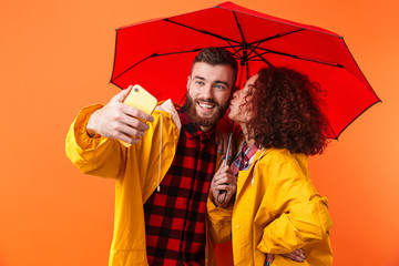 Loving couple posing in yellow raincoats isolated