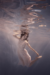 Girl in a dress swims underwater