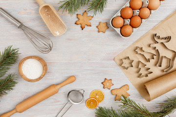 Fototapeta na wymiar Ingredients and kitchen tools for cooking Christmas baking on light wood table top . Flour, eggs, rolling pin, cutters, sieve etc. Top view with copy space.