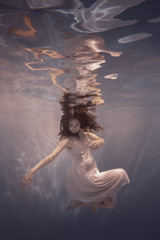 Girl in a dress swims underwater