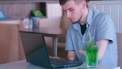 Independent Invalid person. Disabled man freelancer stump hands works in cafe on laptop and drinks cocktail. Handicapped man typing on computer. Problem adaptation to life people with disabilities.