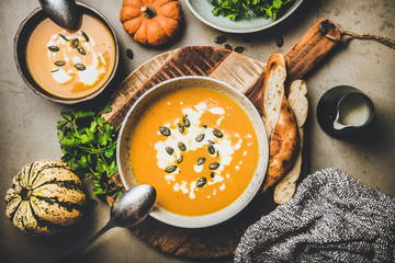 Autumn or winter warming seasonal meal. Flat-lay of pumpkin soup with seeds, parsley and cream in...