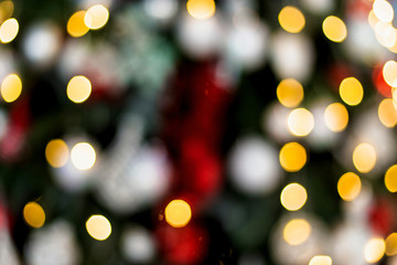 The Christmas tree is decorated with toys, balls, garlands and flowers in blur. Background of lights