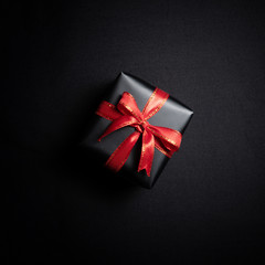 Top view of black gift box with black ribbons isolated on black background.