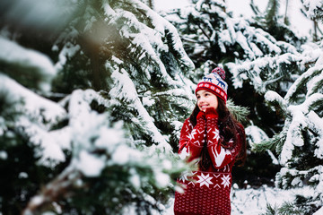  A little girl of European appearance walks in a winter snowy coniferous forest
