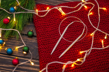 Winter handmade knitting and decorative lights on the wooden table