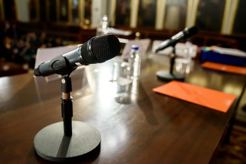 Wireless microphone on a wooden table in a conference room, with no one.