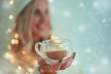 Beautiful smiling young woman in warm clothing with cup of hot tea coffee or punch on snow winter background. Holidays is over here! Close up drink