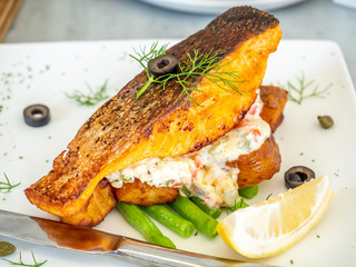 Salmon fish fillet steak served with asparagus, cream salad and lemon in restaurant