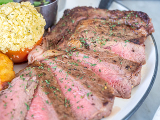Ribeye beef steak medium to well done grilled served with corn, pototoes and asparagus in restaurant