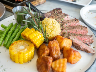 Ribeye beef steak medium to well done grilled served with corn, pototoes and asparagus in restaurant