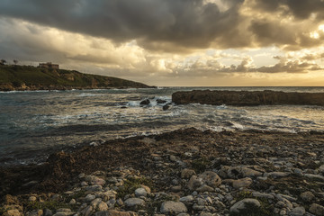 Rocky shore under a cloudy sky at sunset