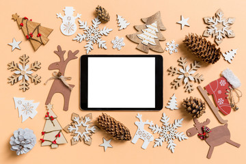 Top view of digital tablet surrounded with New Year toys and decorations on orange background. Christmas time concept