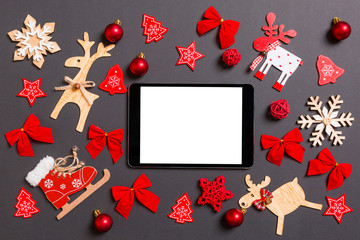 Christmas black background with holiday toys and decorations. Top view of digital tablet. Happy New Year concept