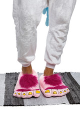 Close-up shot of male legs in white velour trousers and pink plush house slippers made as shaggy...