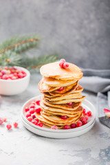 Homemade pancake or hot cake stacked on white plate with berry on grey stone Background, Christmas Dessert.