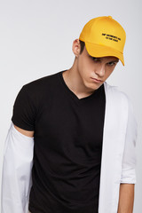 Cropped front view shot of a dark-haired man, wearing yellow baseball cap with lettering 