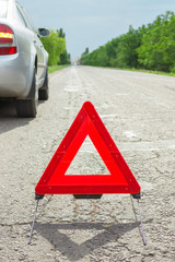 Red triangle of a car on the road. Breakdown of the car in bad weather
