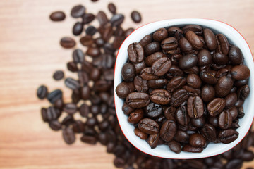 Coffee beans in a coffee mug on an old wooden background and with copy space.