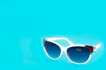 sunglasses in a white plastic frame and blue glasses lenses on a blue background