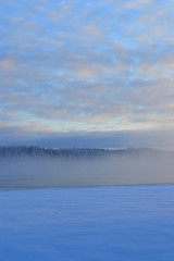 Finnisht winter, Kuusamo, Lake Porontima.. Colorful cloudletts. Mist on the lake .