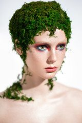 Creative beauty portrait of woman with green moss on her head and colorful makeup
