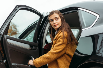 Young woman getting out of taxi and looking away