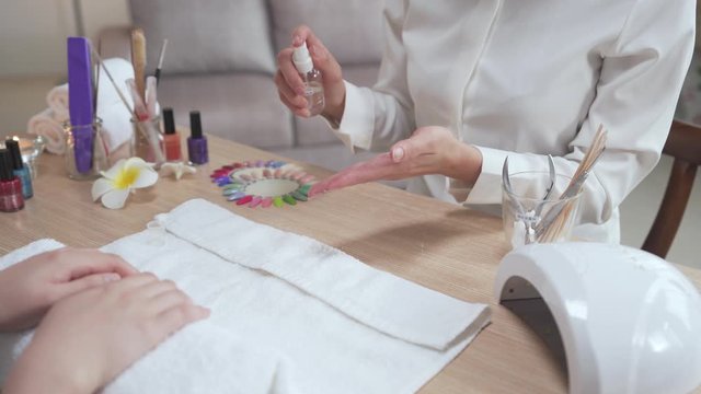 beautician spraying bottle of water on hands at home service to clean. woman worker applying moisturizing liquid for customer before paint on nail. manicure preparation concept.
