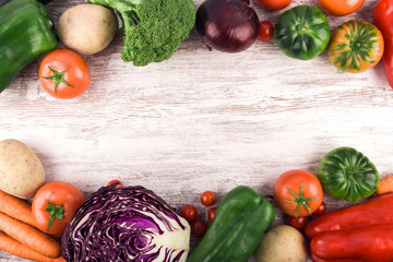 Top view of several fresh and healthy raw vegetables placed to leave a space for text or an image. Rustic white wood background. Copy space. Healthy food. Natural products. Nature and well-being