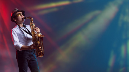Fototapeta na wymiar Junge spielt sein Saxophon auf der Bühne im Lasernebel
