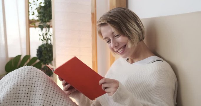 Young woman enjoying reading a book in bed