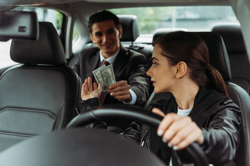 Smiling businessman paying off with taxi driver