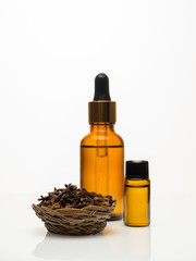 Clove essential oil with dried clove on white background