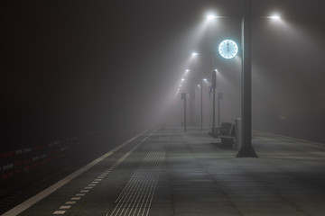 Illuminated, empty platform at a railroad station during a foggy night in autumn. - Powered by Adobe