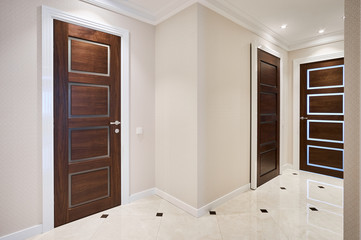 The door is made of walnut wood in a classic style with white architraves in the hallway