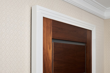 Details doors made of walnut wood in a classic style with the white trim in the hallway